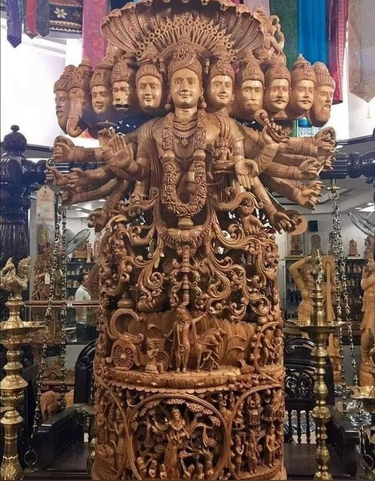 an ornate wooden statue with many faces on it's head and arms, surrounded by other brass objects