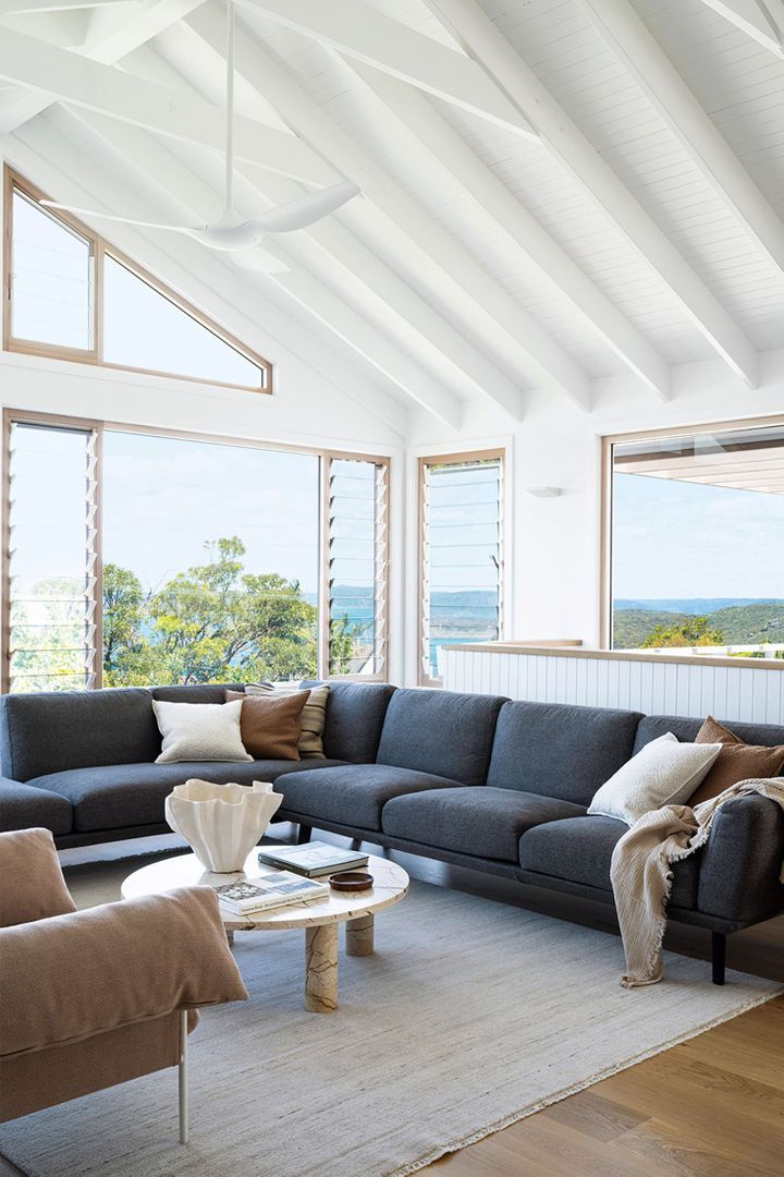 a living room filled with lots of furniture next to large windows on top of a wooden floor