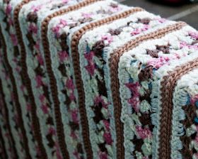 a crocheted blanket sitting on top of a wooden bench next to a red car