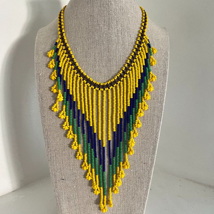 a yellow and green beaded necklace on a mannequin neckpiece with beads