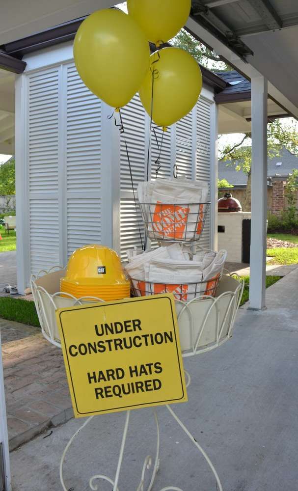 a construction sign and some yellow balloons on a porch with a house in the background