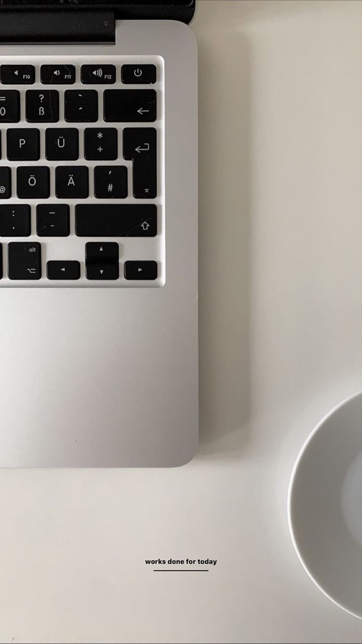 a laptop computer sitting on top of a white desk next to a mouse and coffee cup