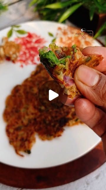 a person holding a piece of food in their hand on a plate with other food items