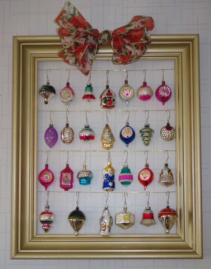 a gold frame with ornaments hanging from it's sides and a bow on top