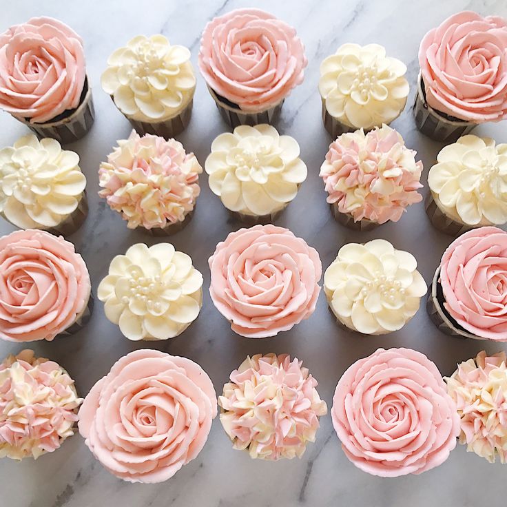 cupcakes with pink and white frosting are arranged on a marble counter top