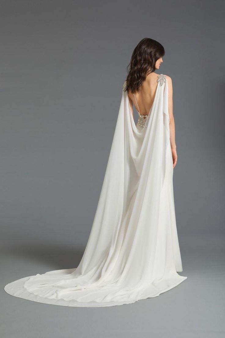 the back of a woman's wedding dress with a cape on her head and shoulders