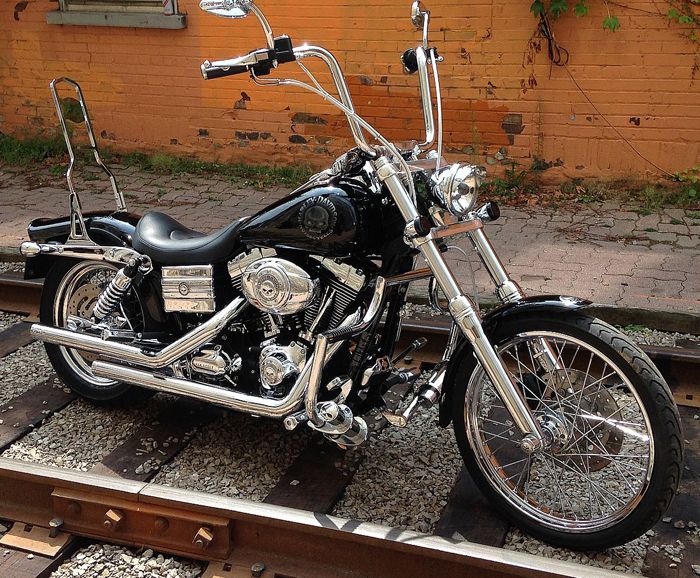 a black motorcycle parked on top of train tracks next to a brick wall and building