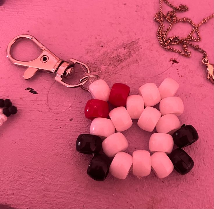 a pair of scissors and some beads on a pink surface next to a chain that is attached to a keychain