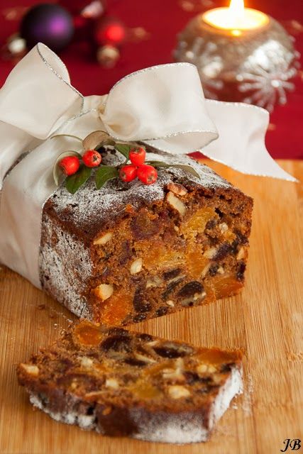 a piece of cake sitting on top of a wooden cutting board next to a lit candle