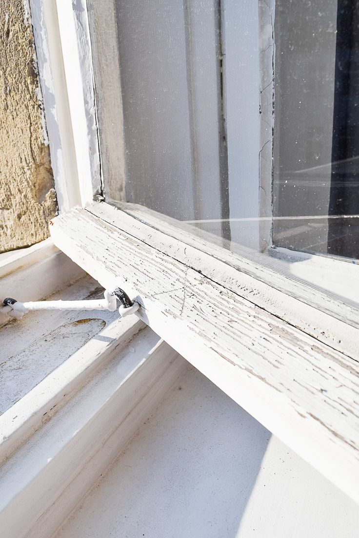 an old window sill sitting in front of a brick wall with peeling paint on it