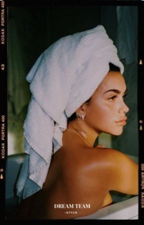 a woman with a towel on her head is sitting in a bathtub and looking off into the distance