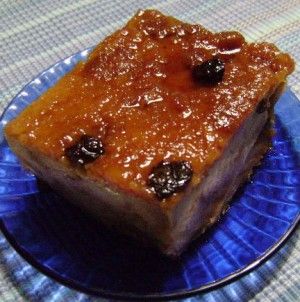 a blue plate topped with a piece of cake covered in caramel and raisins