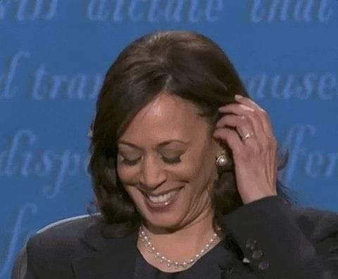 a smiling woman in a black suit and pearls