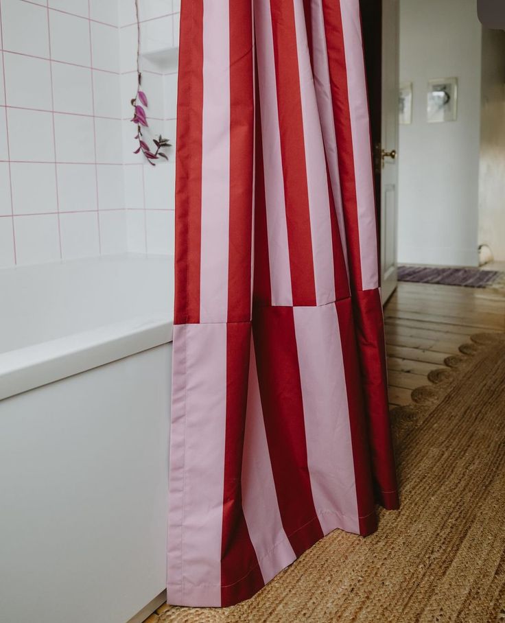 a red and white striped shower curtain next to a bathtub in a home bathroom