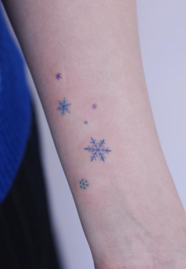 a small snowflake tattoo on the left inner arm and wrist, with stars all over it