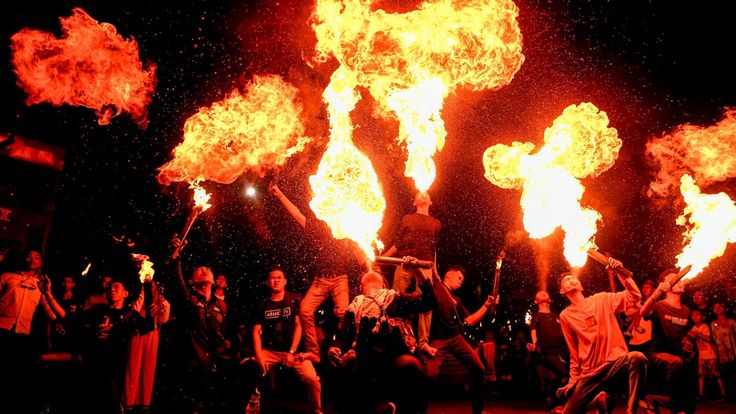 a group of people holding torches in the air with fire coming out of their hands