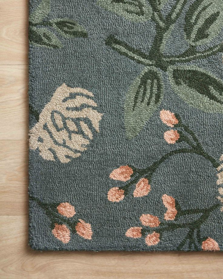 an area rug with flowers and leaves is shown on a wooden floor in front of a wall