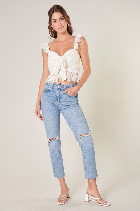 Feel the sun on your skin in this charming ruffled crop top. Embroidered daisies shape this cropped top, featuring ruffle straps that join a fitted bodice with a sweetheart neckline. It maintains a shapely fit with a peplum ruffle along the waistline. A tie front detail sits at the heart of the neckline to create a flirty flair. Wear it with your favorite high rise bottoms for a finished look.- Hook and eye closure- Tie front detail- Embroidered- Peplum- Color: White FloralSize + Fit - Model is Chic Cropped Lace Trim Tank Top, White Cropped Hem Crop Top For Spring, Chic Spaghetti Strap Crop Top With Lace Trim, Feminine Lace Cropped Top, Feminine Fitted Crop Top With Ruffled Straps, Flirty Cropped Top For Spring, Trendy Fitted Crop Top With Ruffled Straps, Summer Lace Trim Cropped Crop Top, Spring Crop Top With Lace Trim And Spaghetti Straps