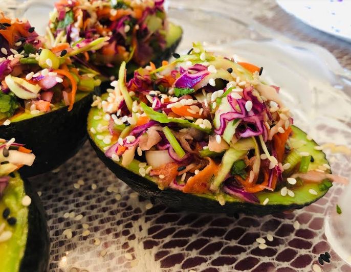 avocado halves filled with coleslaw slaw and sprouts on a plate