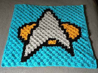 a crocheted blanket with an image of a rocket ship on it