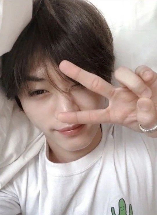 a young man is making the peace sign with his hand while laying in bed next to him