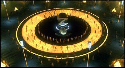 an aerial view of people standing in front of a large circular structure with lights on it