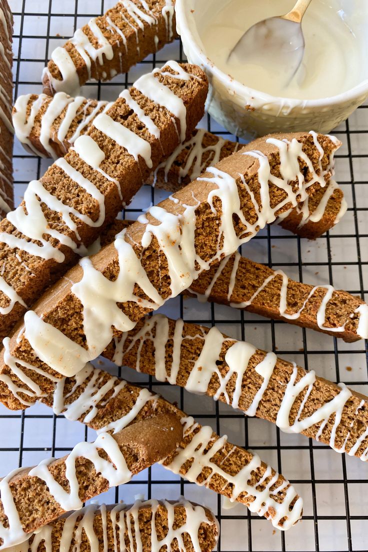 sliced carrot bread with white icing on a cooling rack next to a bowl of yogurt