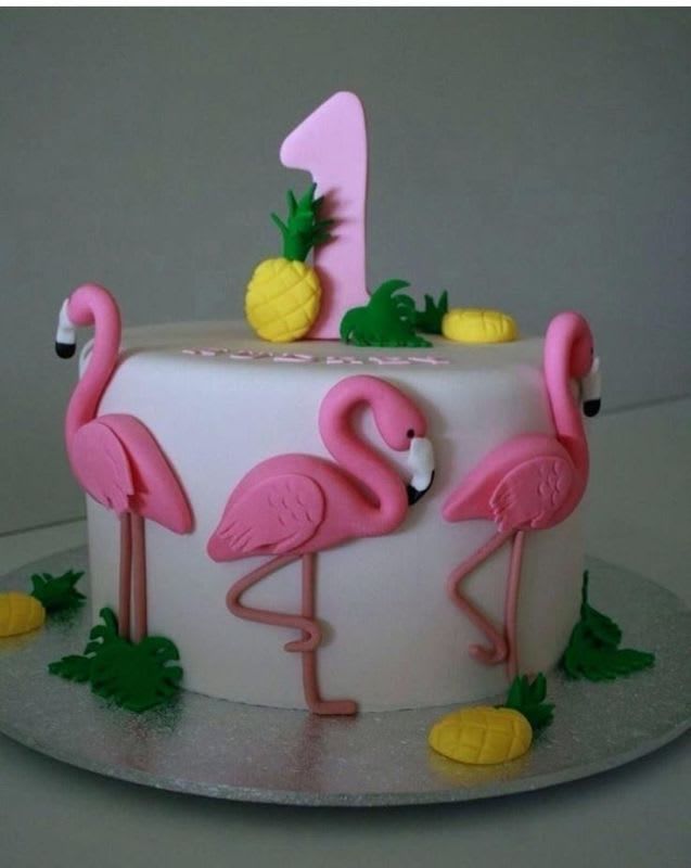 a cake decorated with pink flamingos and pineapples