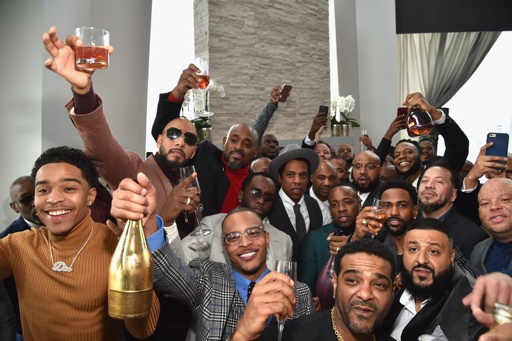 a group of men taking pictures with their cell phones and champagne bottles in front of them