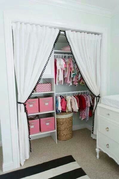 an open closet with white curtains and pink baskets