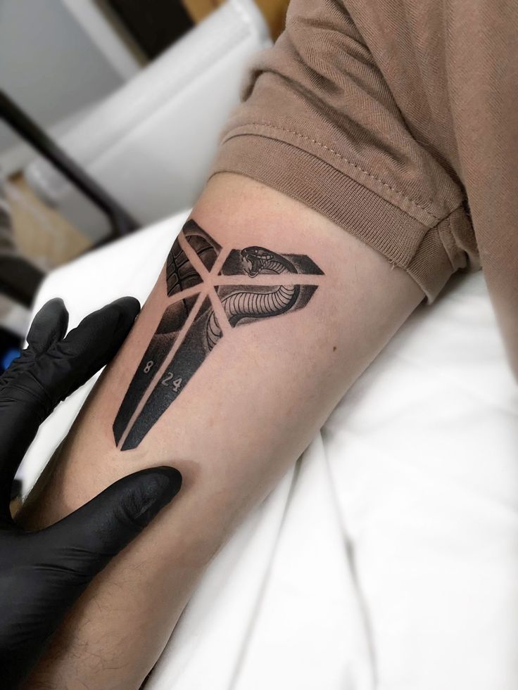 a person with a tattoo on their arm holding onto a black and white object in the shape of a cross