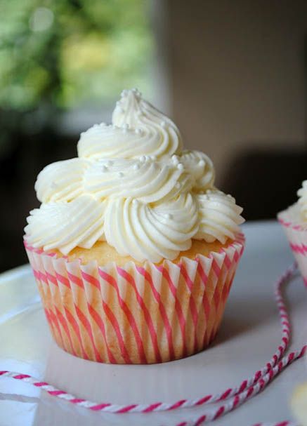 two cupcakes with white frosting sitting on a plate