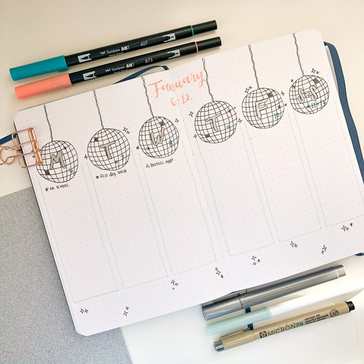 a planner with ornaments hanging from it and two pens on the table next to it