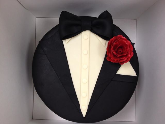 a cake in the shape of a tuxedo with a red rose on it