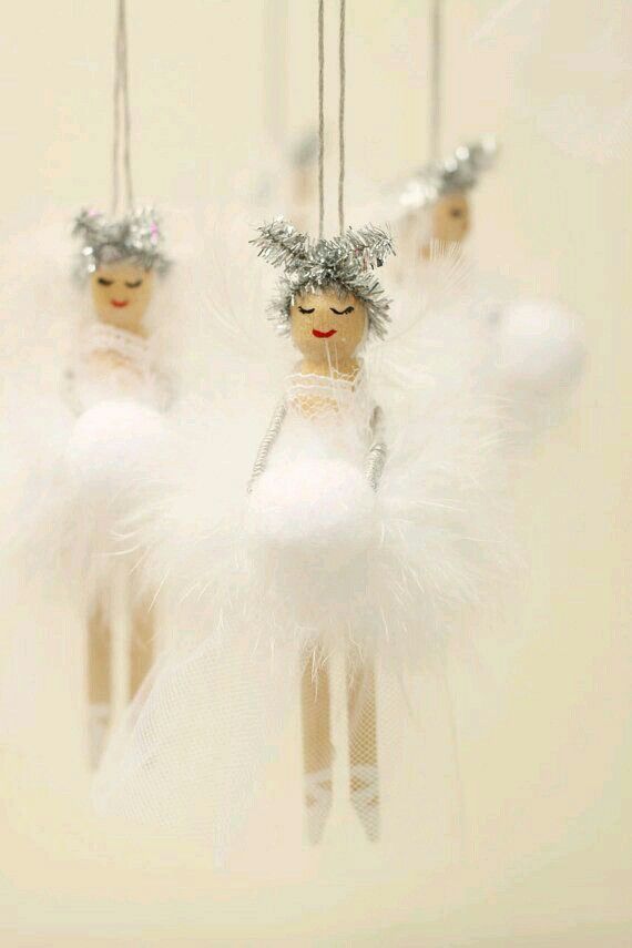 three angel ornaments hanging from strings with white feathers and silver decorations on top of them