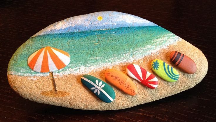 some rocks with different designs on them sitting on a table next to an umbrella and beach ball