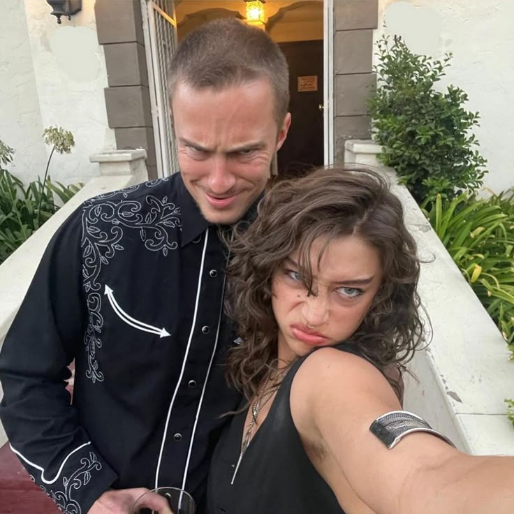 a man and woman taking a selfie in front of a house