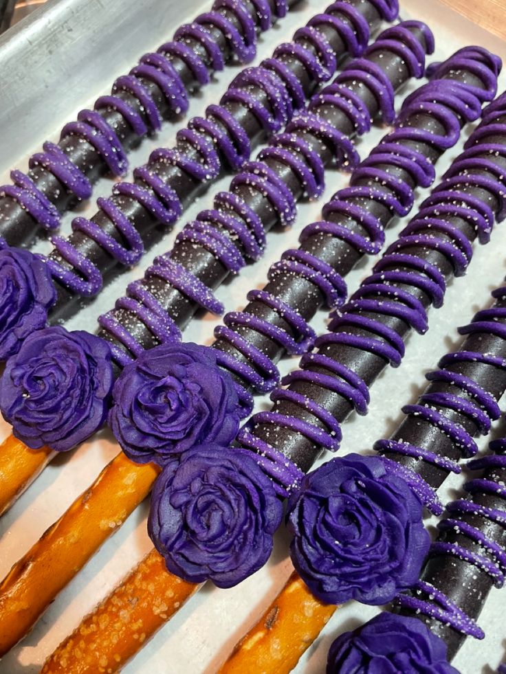 purple icing roses are arranged on sticks in a box with other decorations around them