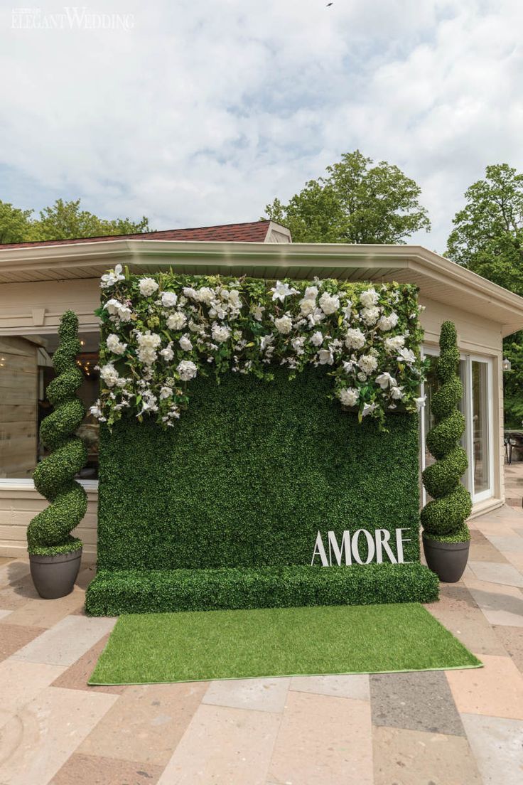 the entrance to an outdoor venue with flowers and greenery on it's side