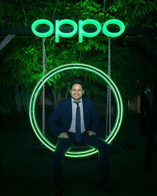 a man standing in front of a neon sign with the word oppo on it