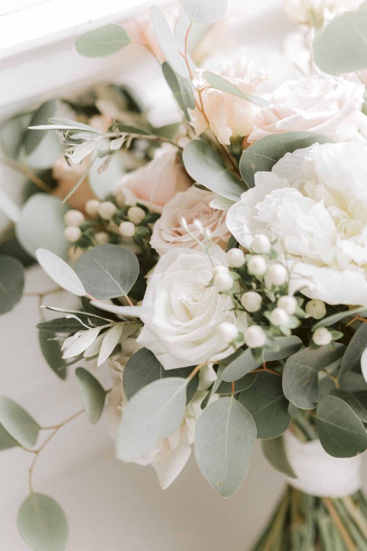 a bouquet of white flowers and greenery on a window sill