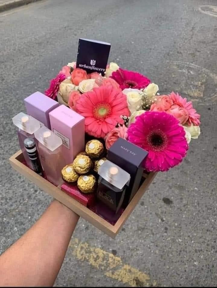 a person holding a box with flowers and chocolates in it on the side of the road