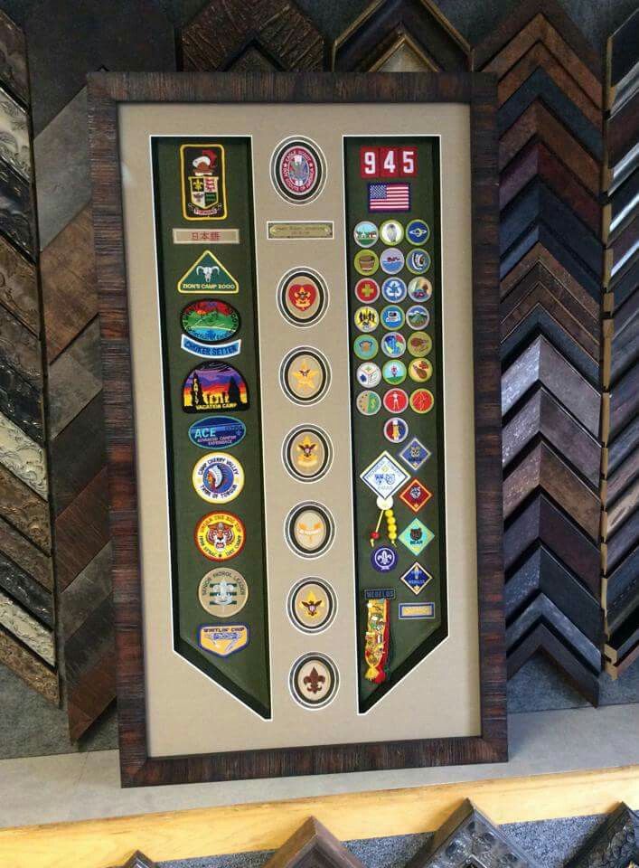 there are many different badges on display in the frame and behind it is a wooden shelf