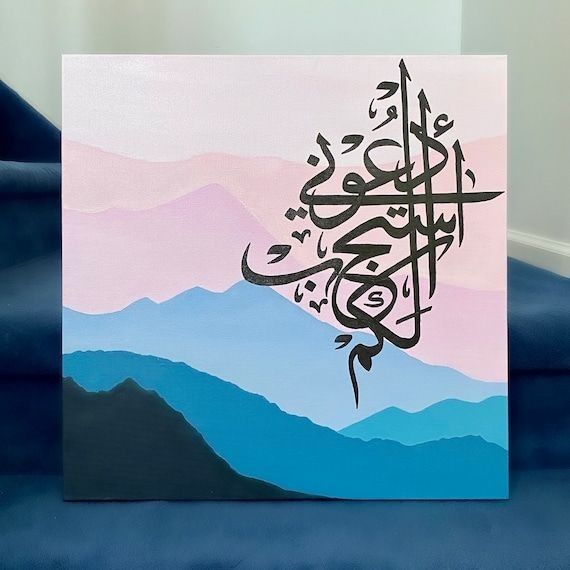 an arabic calligraphy is displayed on a blue couch in front of some mountains and hills