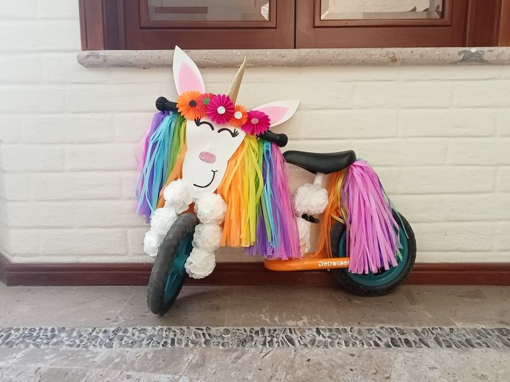 a toy bike with a colorful unicorn on it's front wheel and flowers in the back