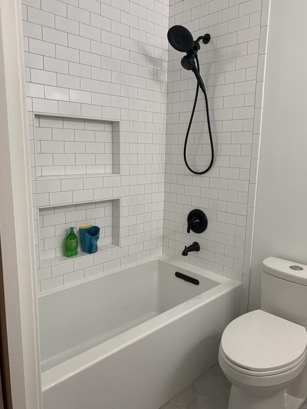 a white toilet sitting next to a bath tub in a bathroom under a shower head