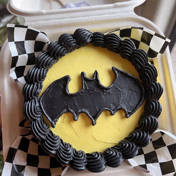 a decorated cake in the shape of a bat on top of a checkered table cloth