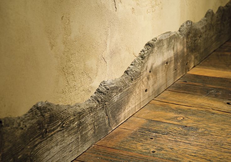 an old wood floor with peeling paint on the wall and wooden planks below it