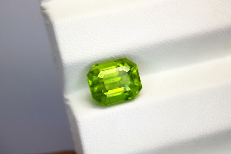 a green diamond sitting on top of a white cloth covered table next to a wall