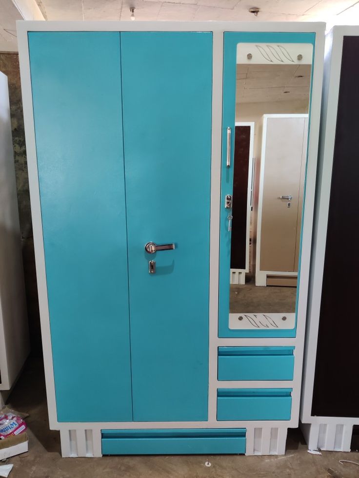 a blue and white armoire sitting next to a mirror on top of a floor